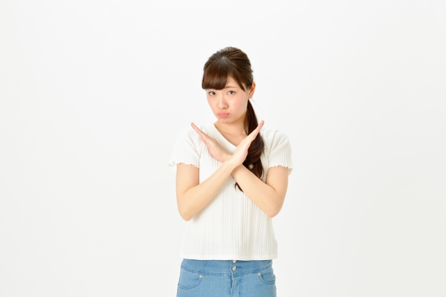 腕でバツ印を作る女性