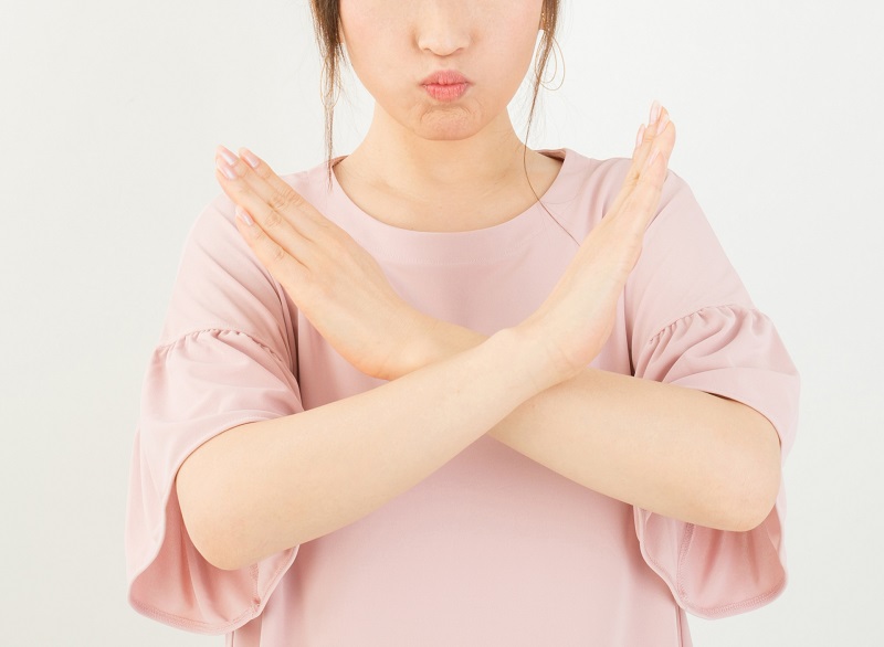 女性が両腕でバツのジェスチャーをしている