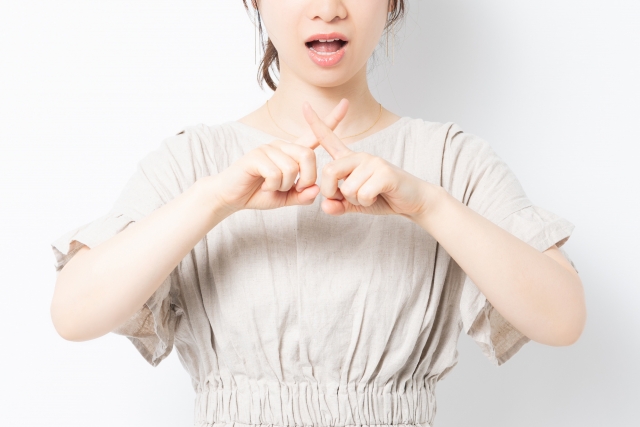 指でバツ印をしている女性