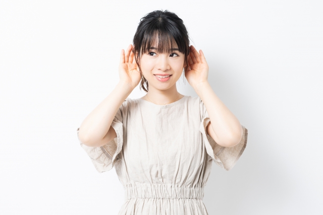 耳に手を当てて聞こうとしている女性